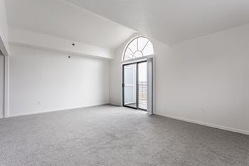 A room with a carpeted floor and a large arched window